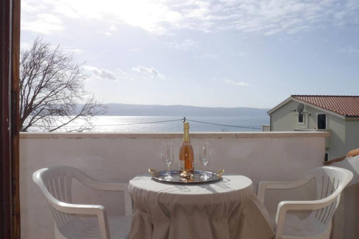 Un balcón con una mesa lista para dos personas, con vista al agua.