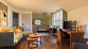 A cozy living room with a sofa, coffee table, and TV area. - Luxurious bungalow for 2 persons (Herpen)