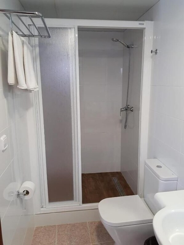 A bathroom with a shower enclosure, toilet, and towel rack. - Pensión La Orozca (Benidorm)