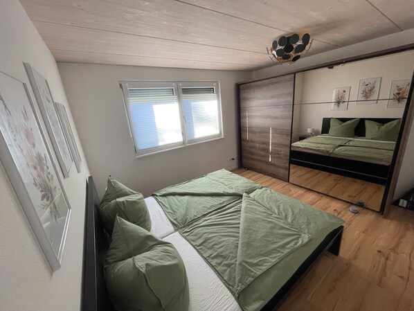 A bedroom with a bed, a window, a mirror, and wall-mounted artwork. - Hegau apartment, 2.5 rooms, 70sqm, free WiFi and parking spaces (Tengen)