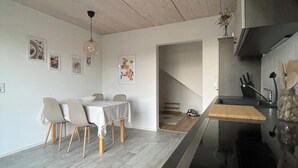 Una cocina moderna con encimera negra, suelo de madera y zona de comedor con mesa y sillas.