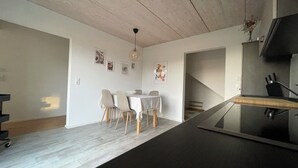 Una cocina moderna con encimera negra, armarios de madera y comedor con mesa y sillas.