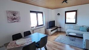 Amplia sala de estar con una mesa de comedor, sillas, un sofá y un televisor.