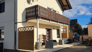 Una casa de dos pisos con balcón, antena parabólica y entrada pavimentada.
