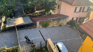 A courtyard with a paved area, a parked scooter, and a car. - Riflessi Sul Lago (Gravedona)