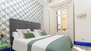 Une chambre à coucher bien aménagée, avec un grand lit, un mur orné d’un motif géométrique et une vue sur l’extérieur par une porte.