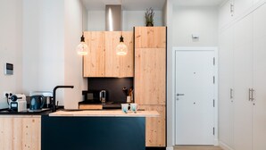 A modern kitchen with wooden cabinets, a central island, and pendant lighting. - Genteel Home Sagasta (Cádiz)