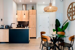 Una cocina moderna con armarios de madera, una isla central y un comedor con mesa y sillas de vidrio.