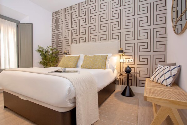 Une chambre d’hôtel moderne avec un grand lit, une table de chevet, une lampe et un panneau décoratif mural.