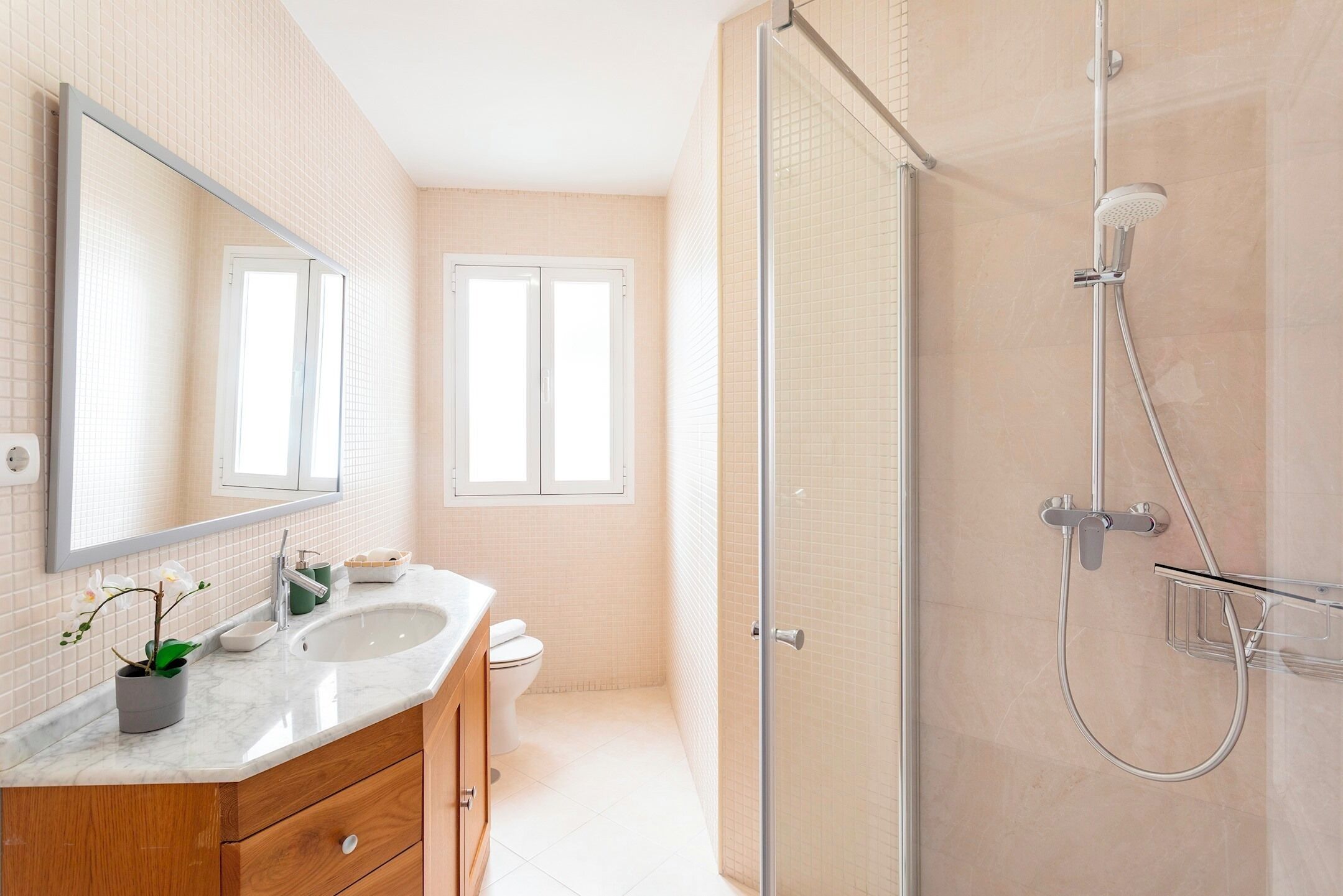 A modern bathroom with a glass shower enclosure, a double sink vanity, and a large mirror.