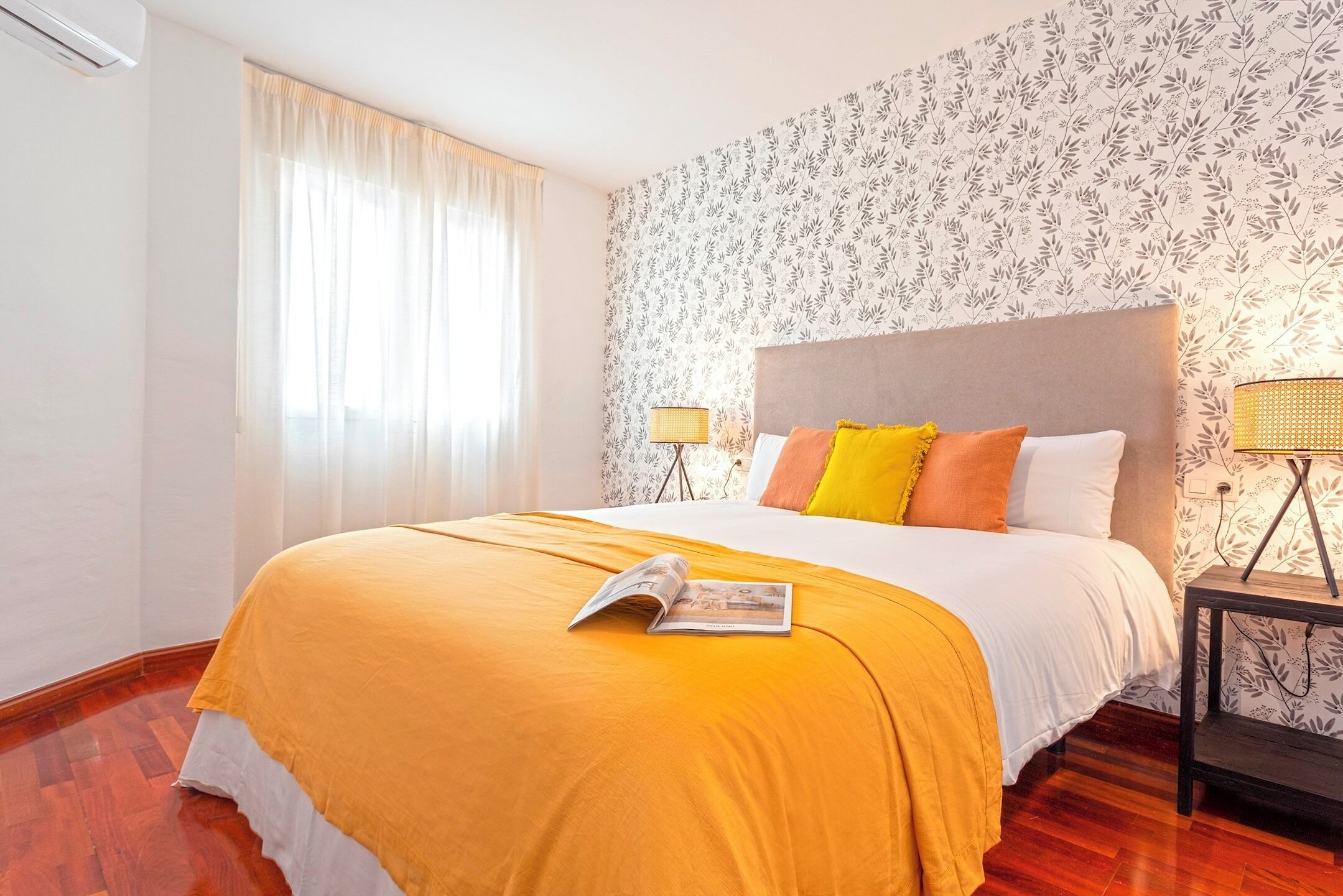 A hotel room with a large bed, a bedside table with a lamp, and a window with curtains.