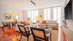 Un salon moderne avec un canapé, des fauteuils, une table basse et un téléviseur.