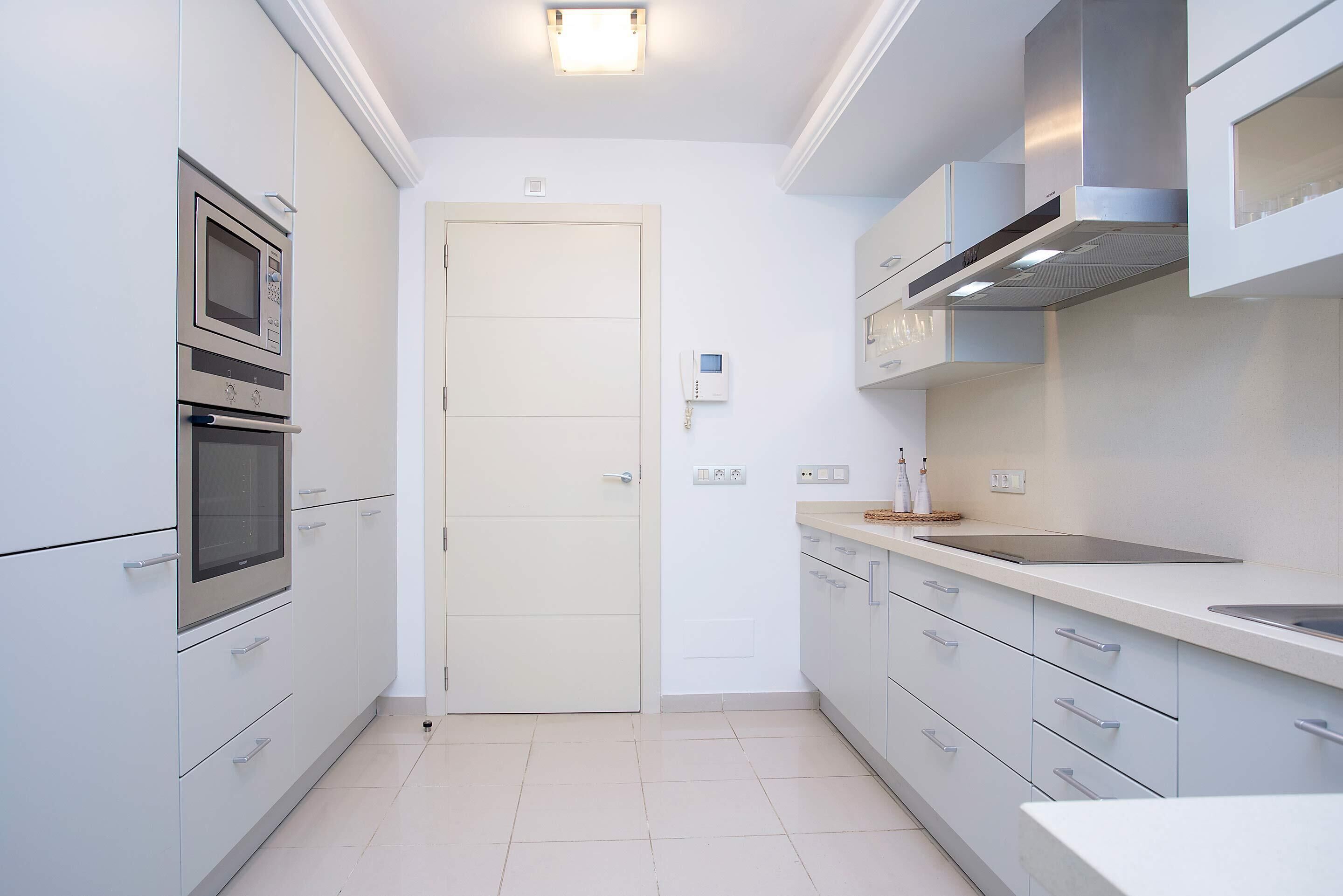 A compact kitchen with a built-in oven, microwave, and stainless steel range hood.