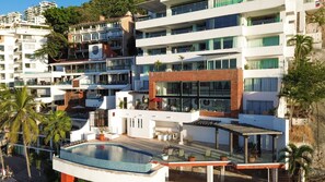 A multi-story hotel with a rooftop pool, outdoor seating, and a view of surrounding buildings. - Caballito del Mar – 2,600 sq. ft. of Beachfront Beauty on Los Muertos Beach (Puerto Vallarta)