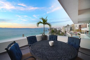 Enjoy a serene view of the water from this balcony, featuring a table and comfortable seating for four.