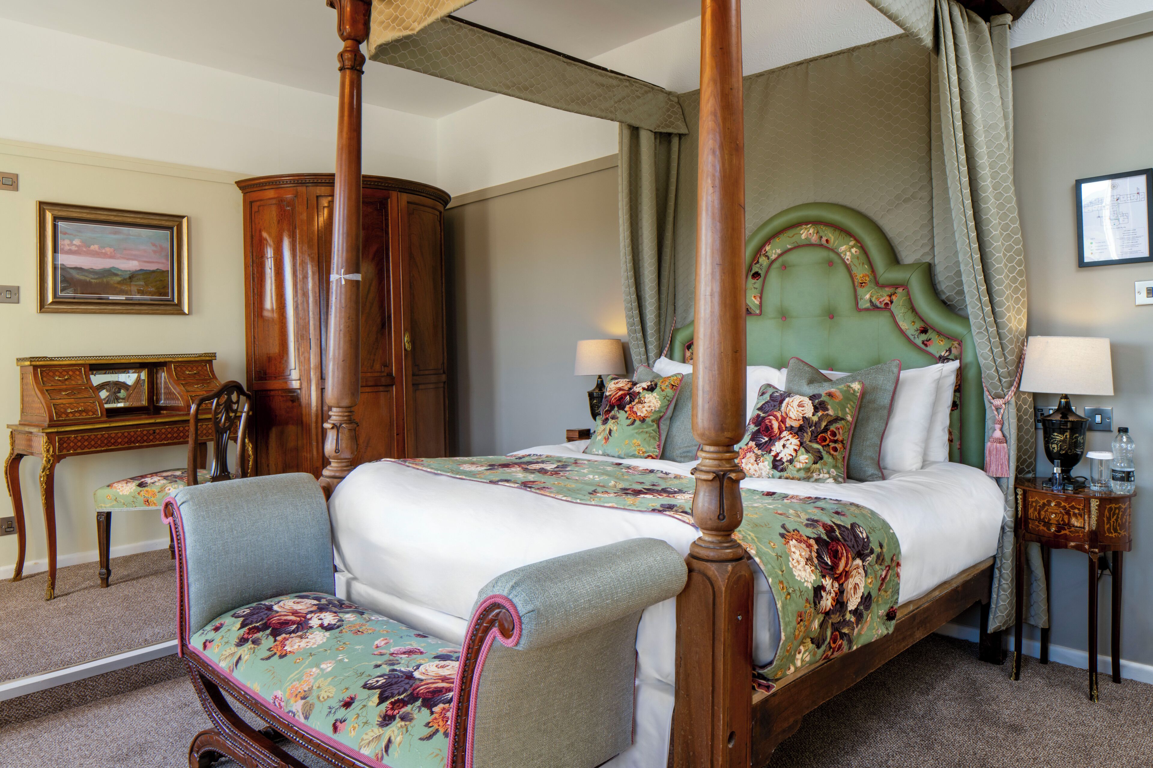 Un lit à baldaquin avec une literie à motifs floraux, une tête de lit en bois et une chaise assortie.