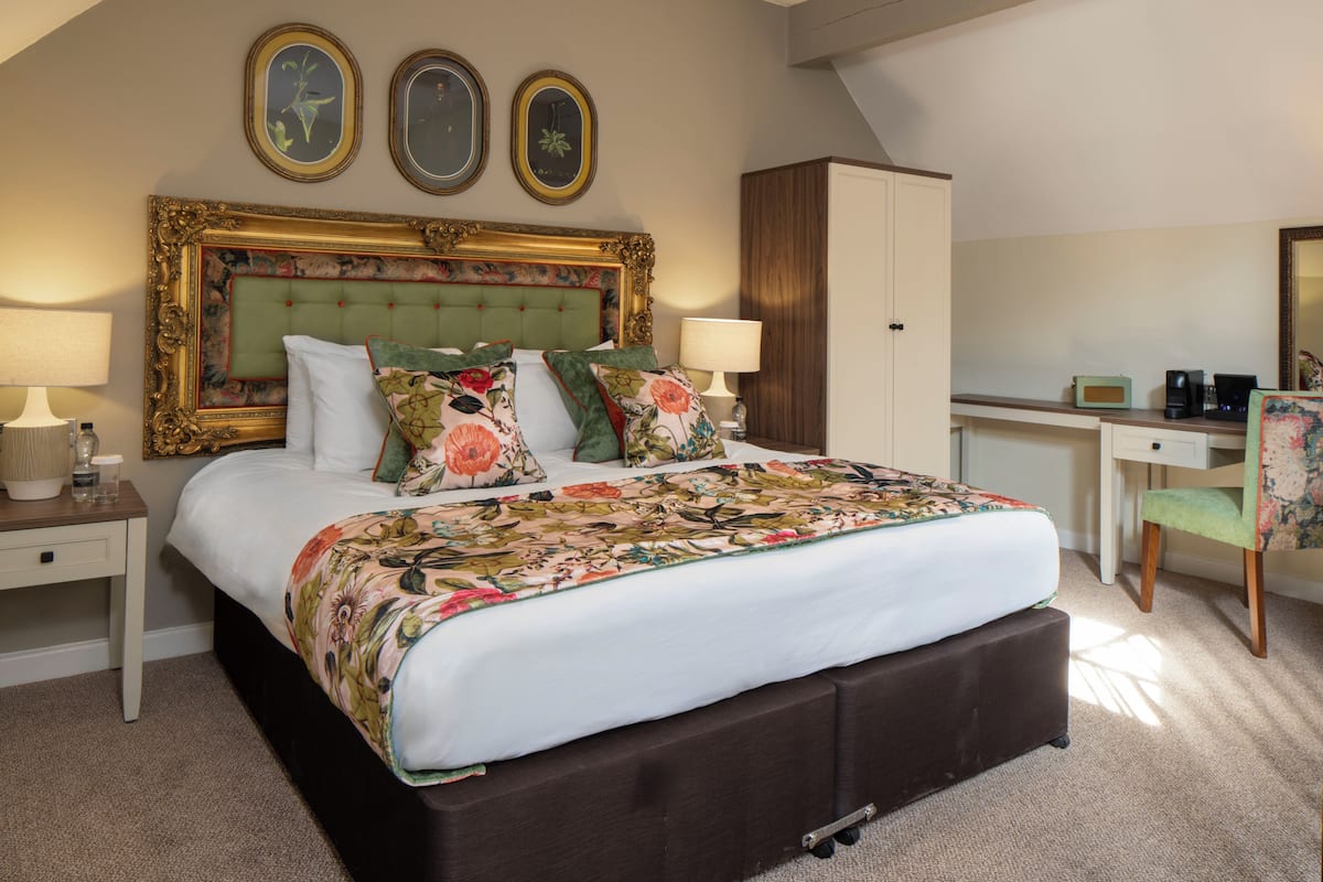 A bedroom with a large bed, two bedside tables, a desk, a chair, and a wardrobe.