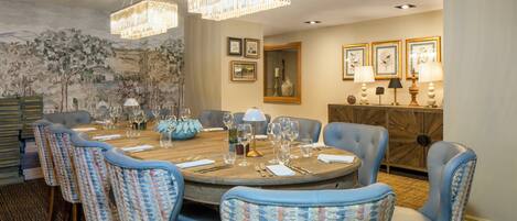 A dining room with a round table set for six, surrounded by six chairs with a patterned fabric.