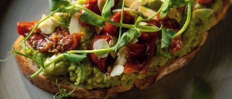 A plate with a food item topped with greens, tomatoes, and other ingredients.