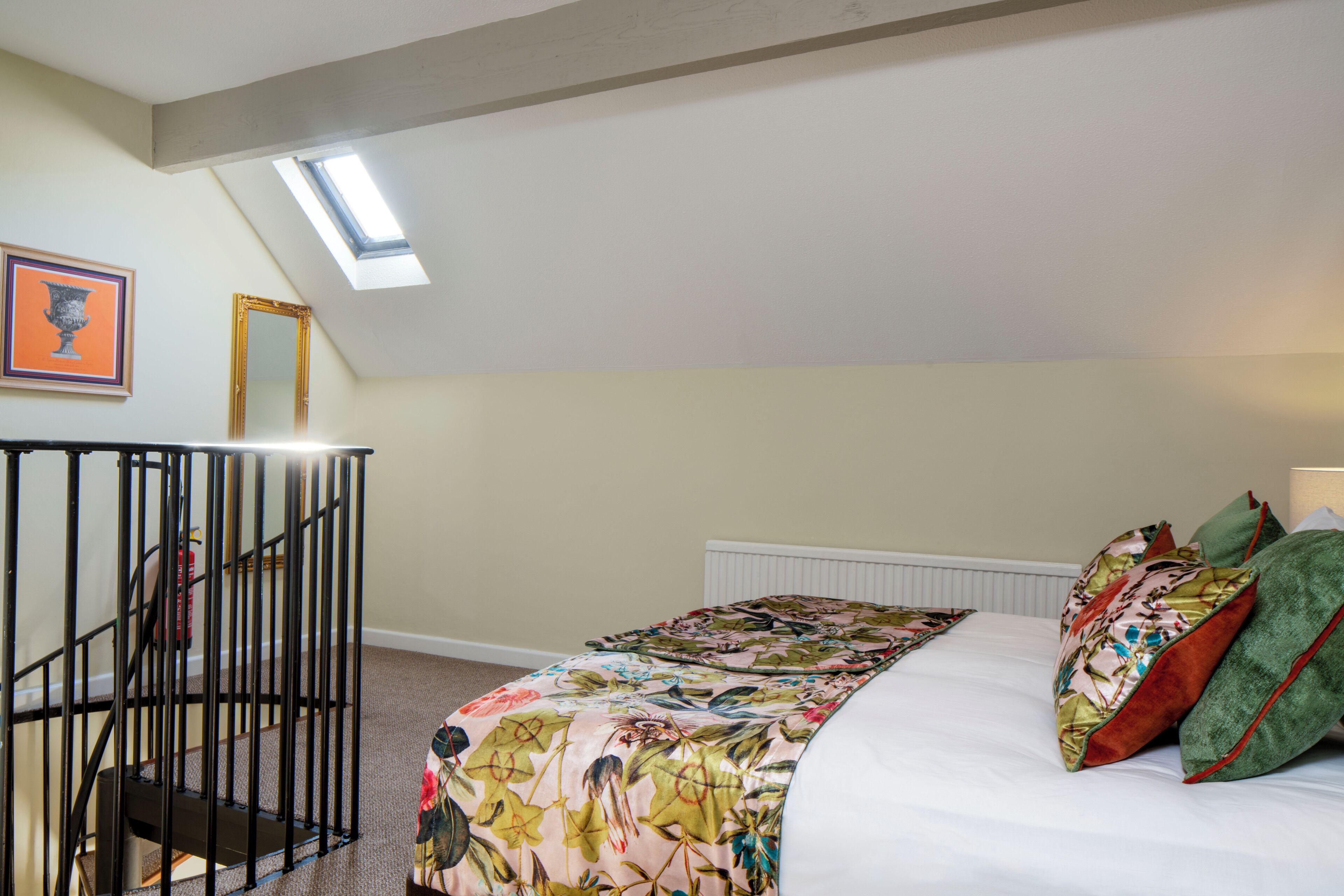Un dormitorio con cama, tragaluz, escalera y radiador.