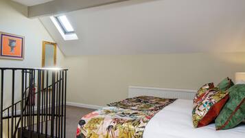 Un dormitorio con cama, tragaluz, escalera y radiador.