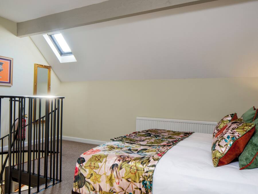 Une chambre à coucher avec un lit, une lucarne, un escalier et un radiateur.