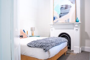 Cozy retreat with a large bed, fireplace, and elegant artwork.