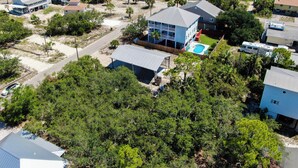 A residential area with multiple houses, a swimming pool, and a beach in the background. - SPACIOUS COVERED RV LOT WITH A LARGE CONCRETE PAD (Port Saint Joe)