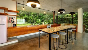 A modern kitchen with a large island, bar stools, and pendant lighting. - The Planchonella House - Eco Stay de Luxe (Edge Hill)