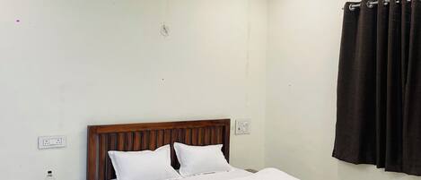 Un dormitorio con una cama de madera, una mesita de noche, un ventilador de techo y una ventana con cortinas.