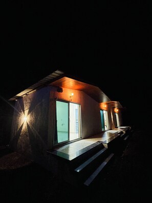 A modern house with a large glass door, a small porch, and a light fixture above the door. - Hotel Sahyadri Agro Farm (Satara)