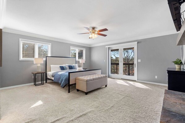 A bedroom with a bed, bedside table, lamp, and a ceiling fan.