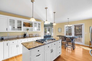 A modern kitchen with white cabinetry, granite countertops, and pendant lighting.