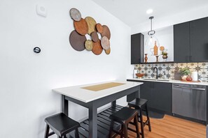 Une cuisine moderne avec un plan de travail blanc, des meubles de couleur foncée et un élément décoratif mural.