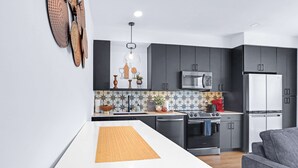 A modern kitchen with dark cabinets, a white countertop, and a central island. - Modern Hill Country Condo for 4 w/ Resort Perks! (New Braunfels)