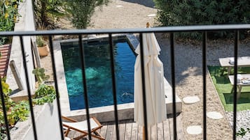 A pool area with a hot tub, deck chairs, and a pergola.