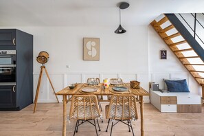 A modern kitchen with a built-in oven and a dining area with a wooden table and wicker chairs. - Villa Lafleur (Châteaurenard)