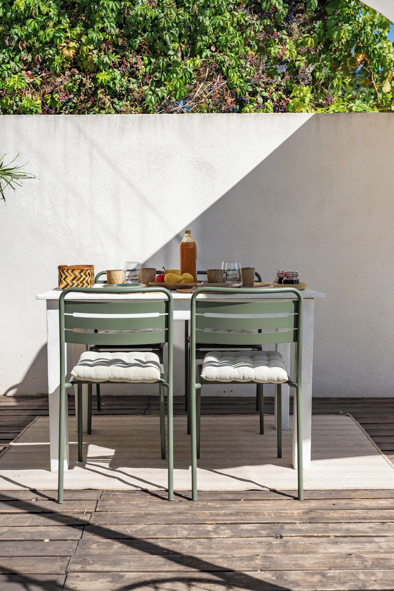 A table with two chairs, a bottle, and a plate with fruits.