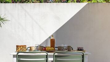 A table with two chairs, a bottle, and a plate with fruits.