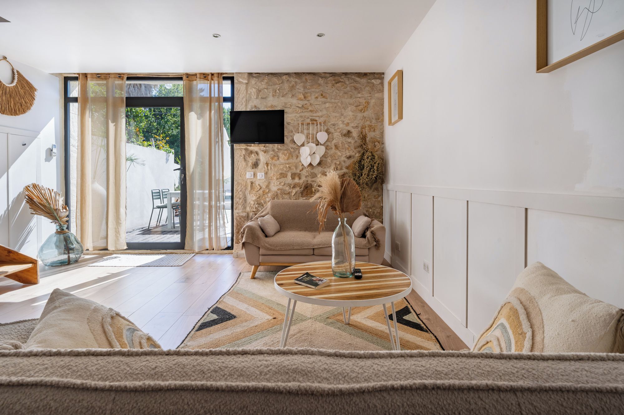 A modern living room with a stone wall, a sofa, a coffee table, and a TV mounted on the wall.