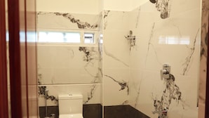 Une salle de bain avec des toilettes, un lavabo et une douche.