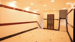 Un vaste hall d’entrée doté d’un sol en marbre, de boiseries le long des murs et d’un escalier menant à l’étage supérieur.