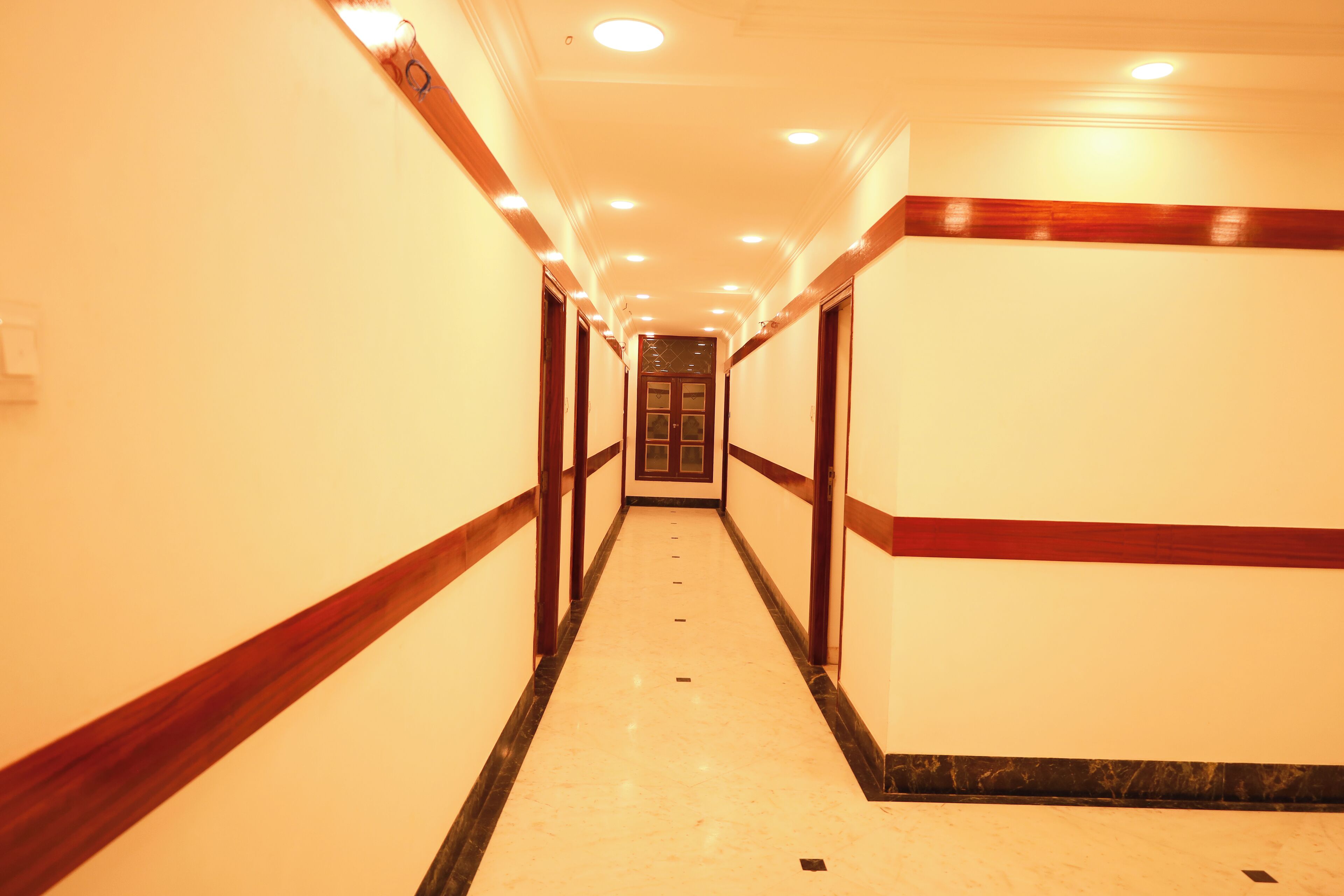 A long, narrow hallway with a marble floor and wooden trim.