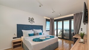 Une chambre d’hôtel moderne avec un grand lit, un bureau et un balcon offrant une vue agréable.