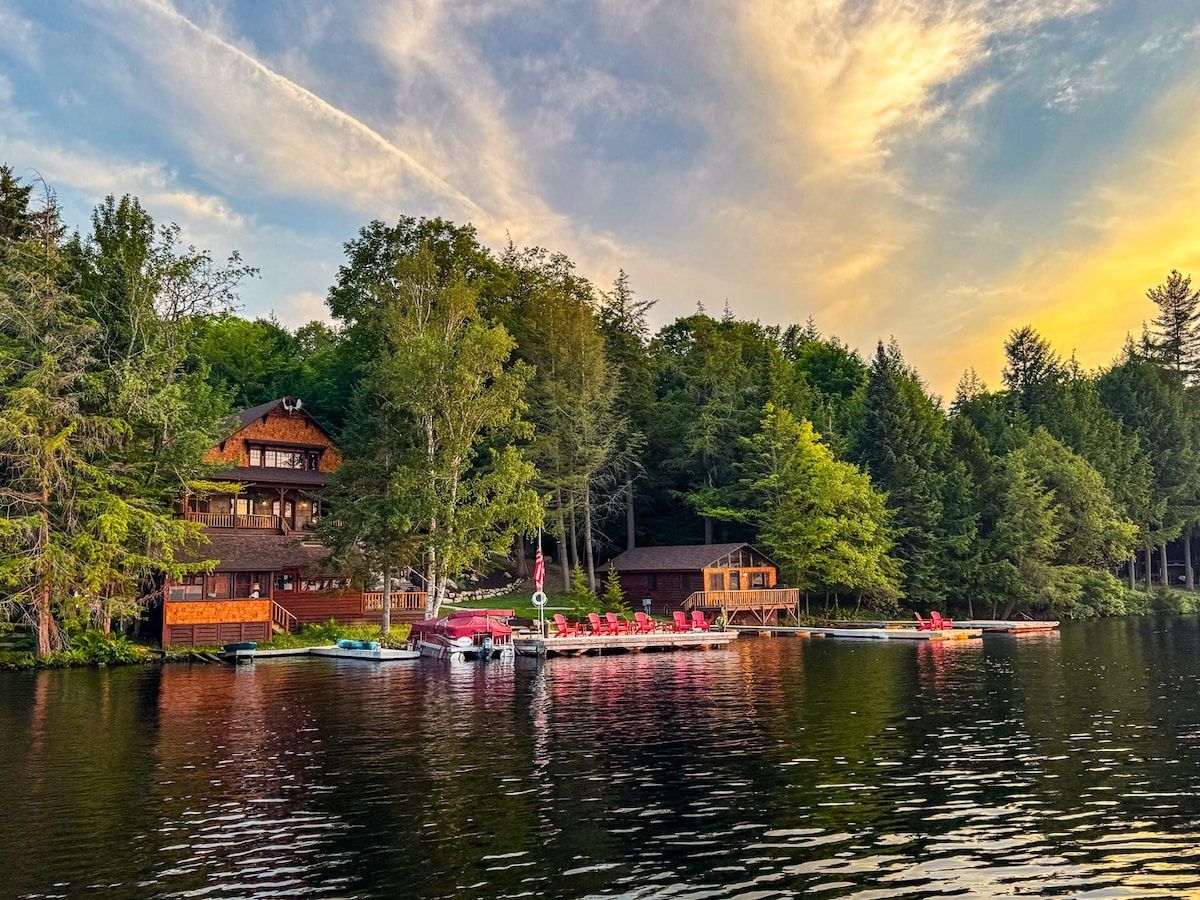 Un chalet au bord du lac, doté d’un quai, et entouré d’une forêt dense.