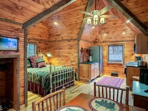 A cozy log cabin interior with a bed, a dining table, and a kitchen area. - Lakeside Lodge on 7th Lake - The Carriage House (Inlet)