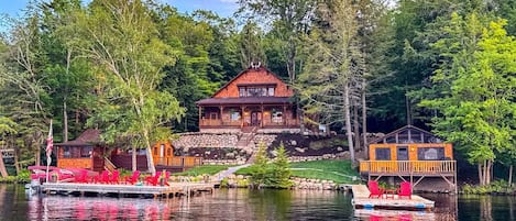 A lodge with a dock, a covered area, and a building with a red roof.