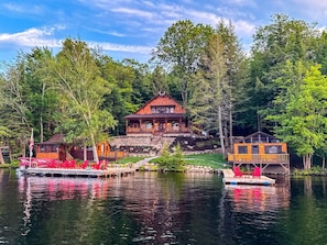 A lodge with a dock, a covered area, and a building with a red roof. - Lakeside Lodge on 7th Lake - The Carriage House (Inlet)