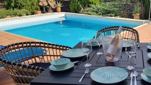 A poolside table set with plates, cutlery, and a glass pitcher, surrounded by wicker chairs. - Plaka Elounda ..private Pool ..2 Beds..jaccuzi..parking..spinalonga/sea Views (Agios Nikolaos)