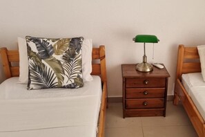 A bedroom with two wooden beds, a nightstand with a lamp, and a pillow with a leaf pattern.